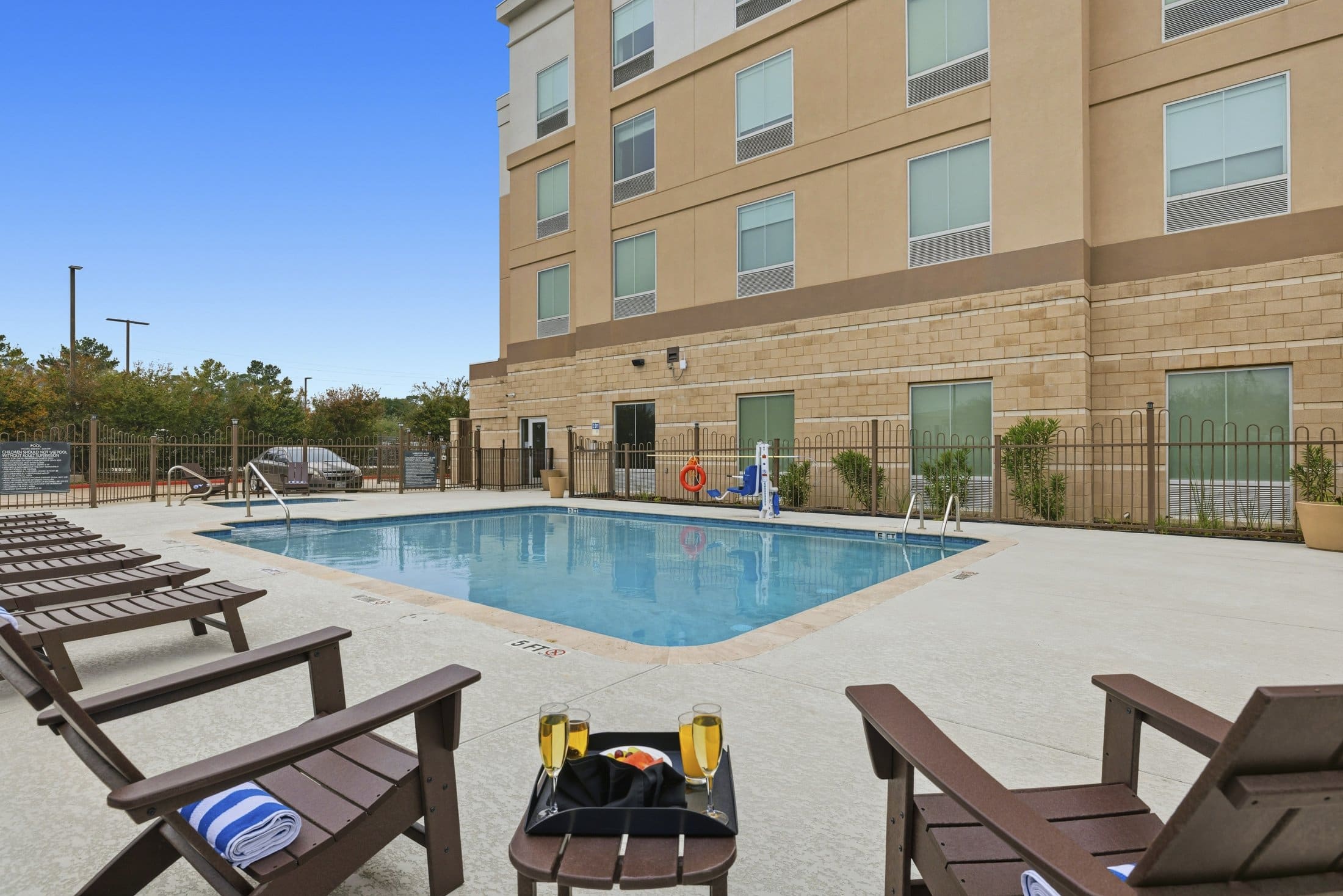 A hotel pool area with lounge chairs, towels, and champagne.